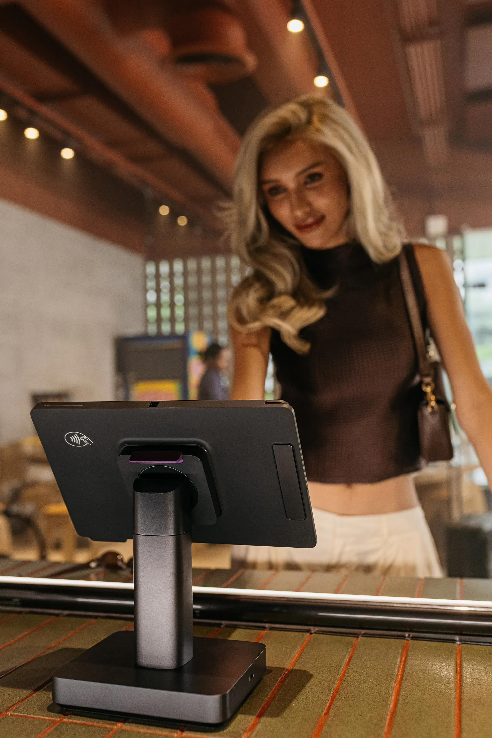 A customer smiling as she looks down at a counter terminal