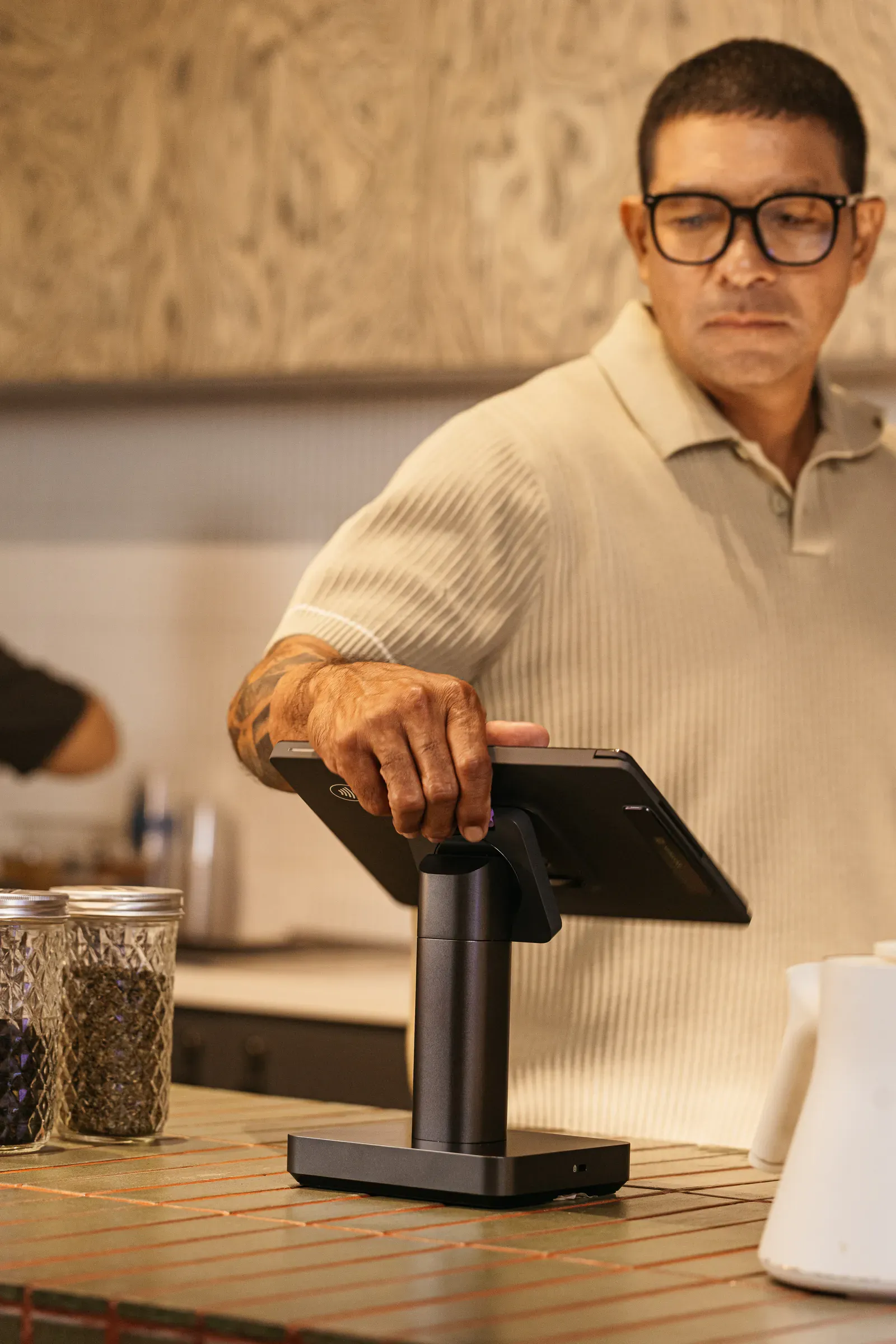 A café operator resting a hand on a counter terminal